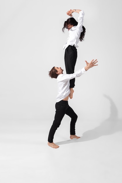 Bailarines de ballet jóvenes y elegantes en estilo negro mínimo aislado sobre fondo blanco de estudio