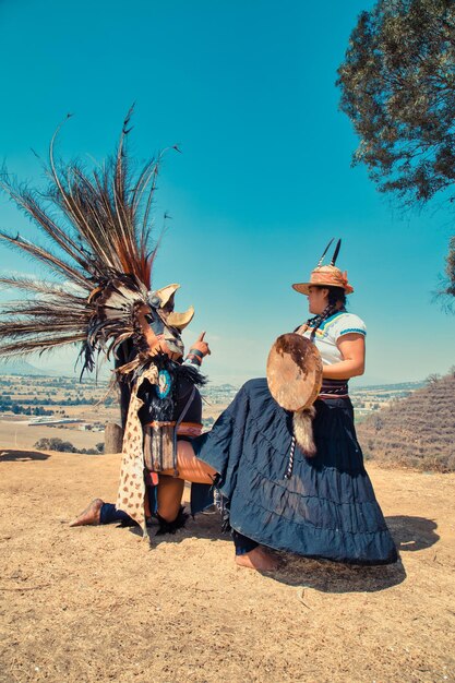 Bailarines mexicanos posando ante la cámara con mechones y vestimenta prehispánica