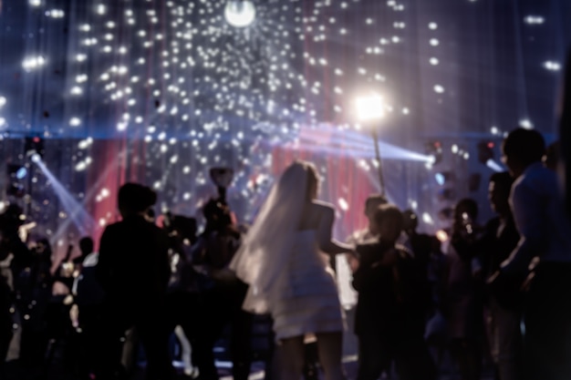 Baile feliz borroso del novio y de la novia del concepto en el banquete de boda con la huésped.