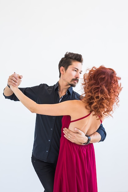 Foto baile social, bachata, kizomba, salsa, concepto de tango - mujer vestida de rojo y hombre de negro