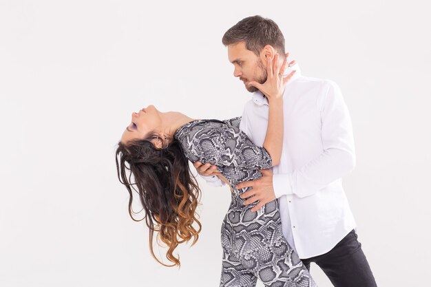 Baile social, bachata, kizomba, zouk, concepto de tango - El hombre abraza a la mujer mientras baila sobre blanco