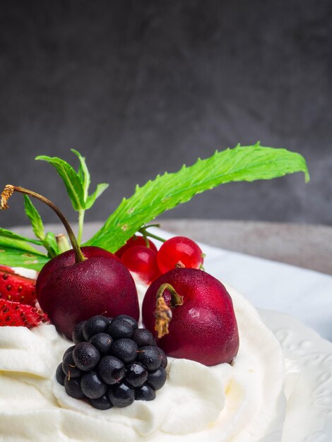 Baiser-Pavlova-Kuchen mit frischer Kirschbrombeerdbeere auf konkretem Hintergrund