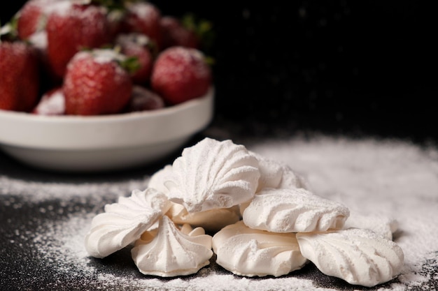 Baiser und Erdbeeren in einem Teller auf schwarzem Hintergrund