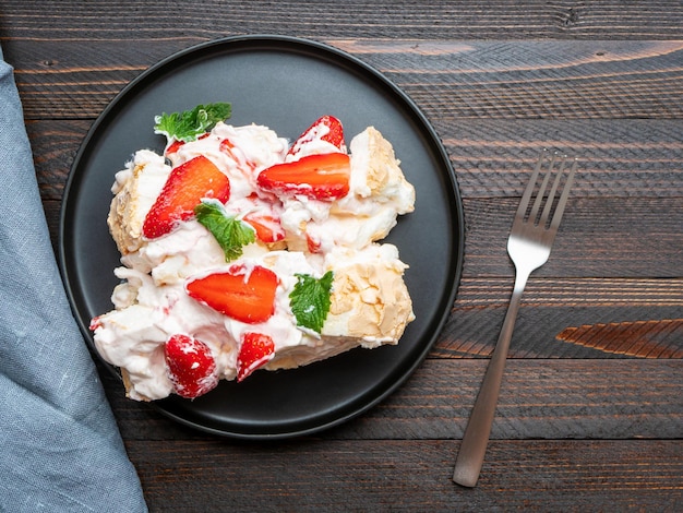 Baiserroulade Baiserrollenkuchen Pavlova mit Sahneerdbeeren und Minzblättern Draufsicht