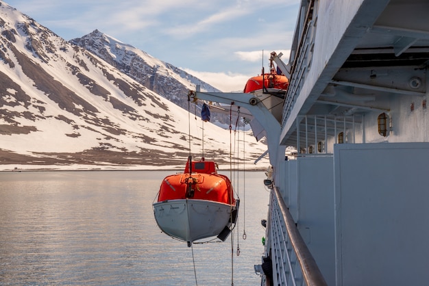 Bajando el bote salvavidas naranja al agua en las aguas del Ártico