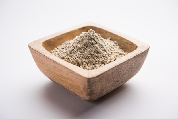 Bajra atta o harina de mijo perla en polvo servido en un recipiente con una pequeña cuchara de madera, el enfoque selectivo