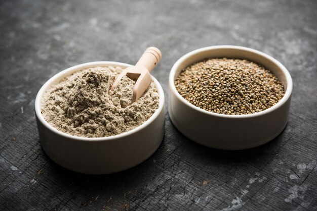 Bajra, mijo perla o granos de sorgo con harina o polvo en un recipiente, el enfoque selectivo