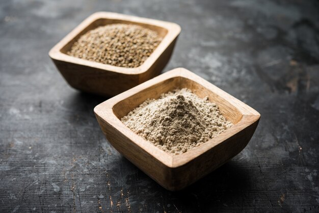 Bajra, mijo perla o granos de sorgo con harina o polvo en un recipiente, el enfoque selectivo