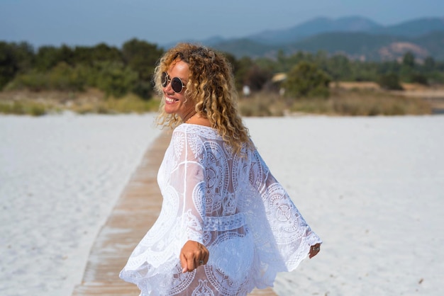 Bak vista de mulher adulta com roupa de praia branca andando feliz e livre na praia na areia branca no destino de férias de verão tropical Mulheres alegres em atividade de lazer ao ar livre