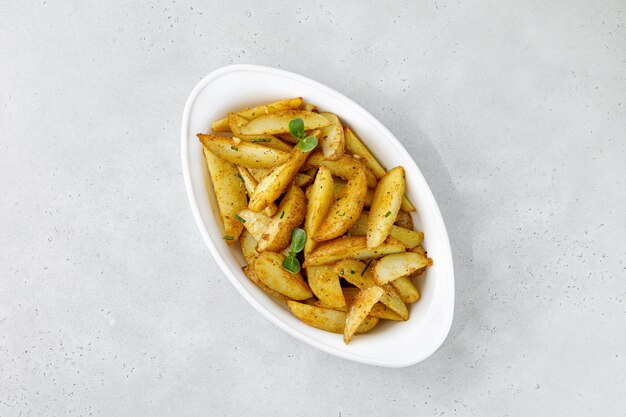 Baked Potato Wedges in weißer Auflaufform Bratkartoffeln mit Kräutern und Gewürzen Kopieren Sie Platz