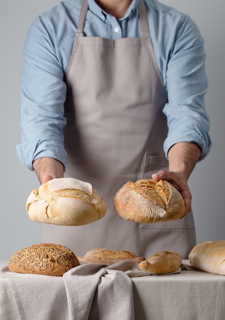 Baker com uma camisa jeans mostra dois pães