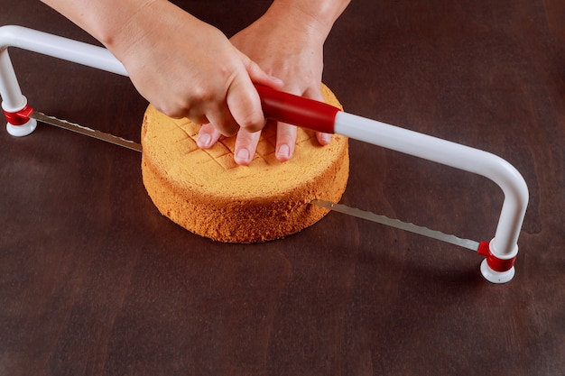 Baker cortando la parte superior del pastel con un pastel nivelador dentado. Hacer un pastel de capas.