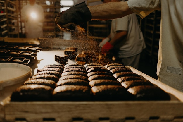 Baker espolvorea harina sobre los panes de estilo rústico antes de hornear pan rústico de grano entero con semillas de girasol