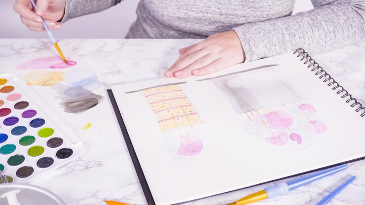 Foto baker está dibujando el diseño de un pastel de cumpleaños con acuarelas.