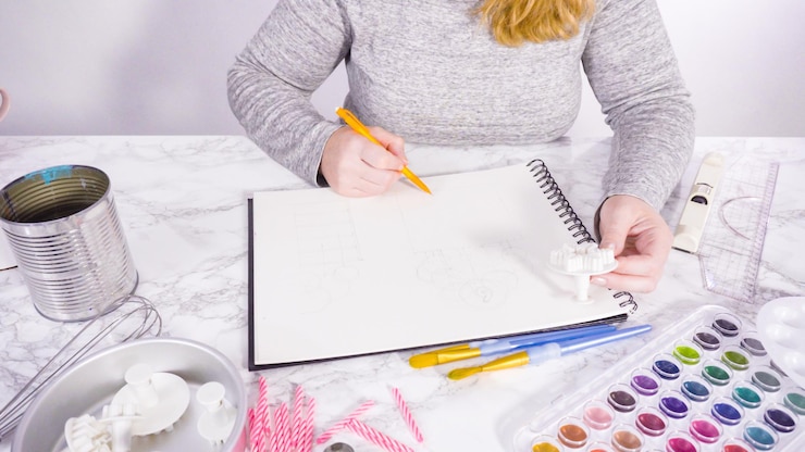 Foto baker está dibujando el diseño de un pastel de cumpleaños.