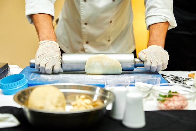 Baker extiende la masa sobre una mesa de cocina de madera espolvoreada con harina