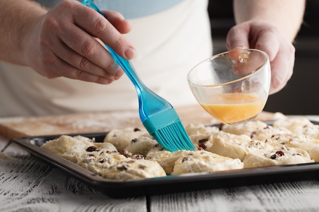 Baker legt kurz vor dem Backen einen Schneebesen auf frisch aufgerollte Mini-Croissants