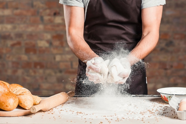 Foto baker mezcla amasar masa con harina en la encimera de la cocina