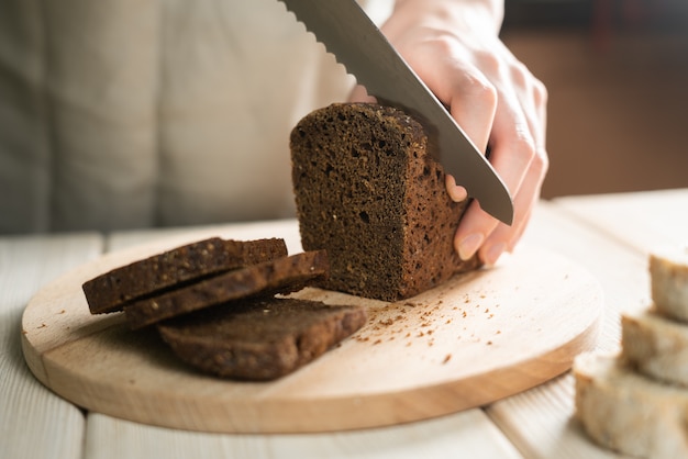 Baker schneidet frisches Brot in dünne Scheiben