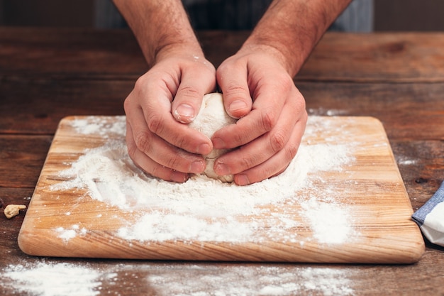 Baker sosteniendo la masa cruda en primer plano de las manos