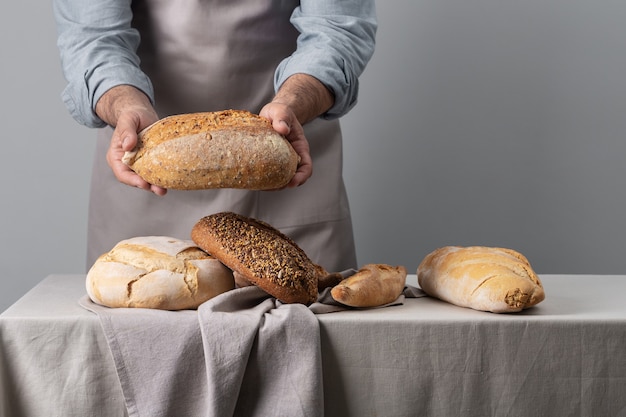 Baker sosteniendo pan recién horneado sobre la mesa sobre fondo gris con espacio de copia