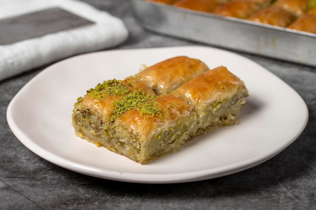 Baklava com pistache em fundo escuro Baklava tradicional turca em um prato Fotografia de estúdio em close-up