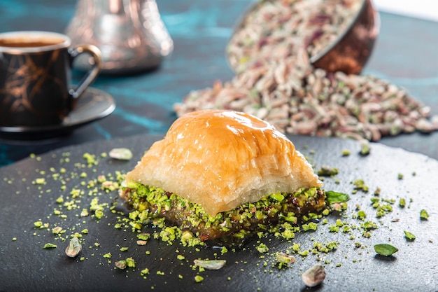 Foto baklavas de pistache grego turco com café tradicional turco na mesa de fundo de mármore preto