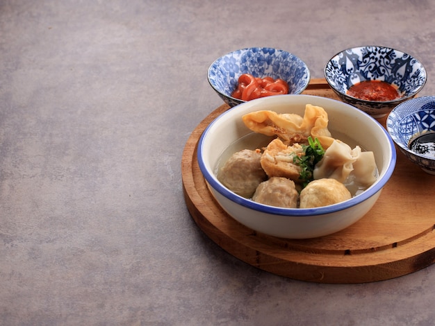 Bakso Malang, Fleischbällchensuppe mit verschiedenen Beilagen wie Tofu Fried Shiumay oder Bakso Goreng. Auf dem Tisch serviert mit Sambal, Sojasauce und Tomatensauce. Ausgewählter Fokus