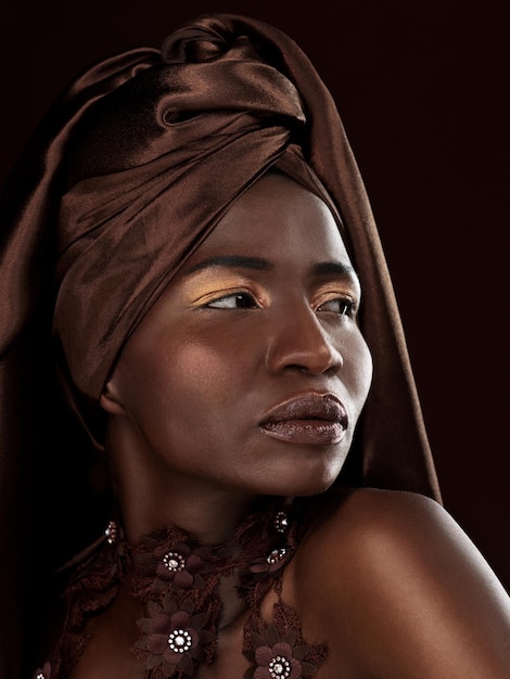 Balanceando su envoltura de cabeza Foto de estudio de una atractiva mujer joven posando con atuendo tradicional africano contra un fondo negro