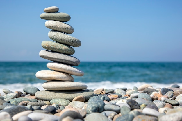 Balancieren Sie eine Pyramide aus glatten Steinen auf dem Meer