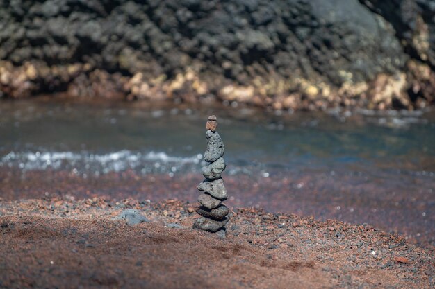 Balancierende Pyramide aus Meereskieseln auf Strandhintergrund, das Konzept der Harmonie und des Gleichgewichts. Steine balancieren.