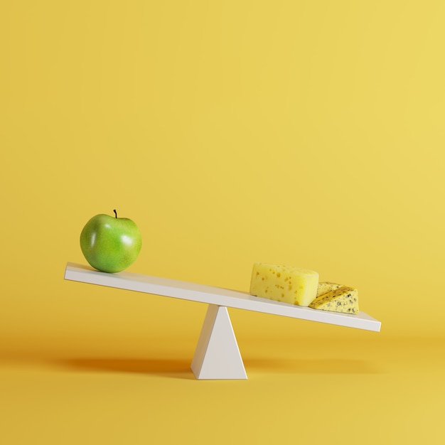 Foto balancín de queso inclinado con manzana verde en el extremo opuesto sobre fondo amarillo.