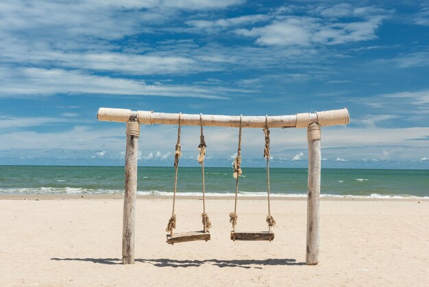 Foto balanço de corda de madeira na areia branca contra o mar e o céu azul no verão na praia cha-am, petchaburi, thaialnd. férias de viagem tropical. local para relaxar e se refrescar com uma atmosfera fresca.