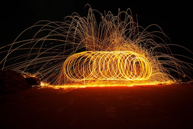 Balanço de fogo Redemoinho fotografia de luz de lã de aço sobre a pedra com reflexo na água Bela luz no nascer ou pôr do sol tempo de longa exposição velocidade estilo de movimento