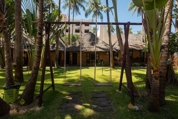 Balanço de madeira pendurado em um belo jardim perto do bangalô O território interno de um belo hotel à beira-mar Pequenas casas no resort na Ásia