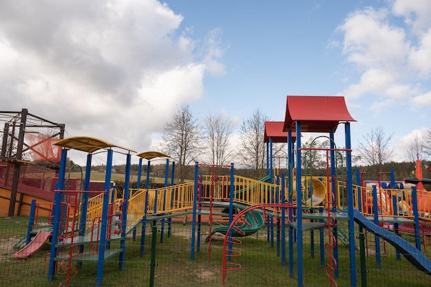 Balanço infantil vazio no parque, bancos de madeira, escorregadores, equipamentos esportivos.