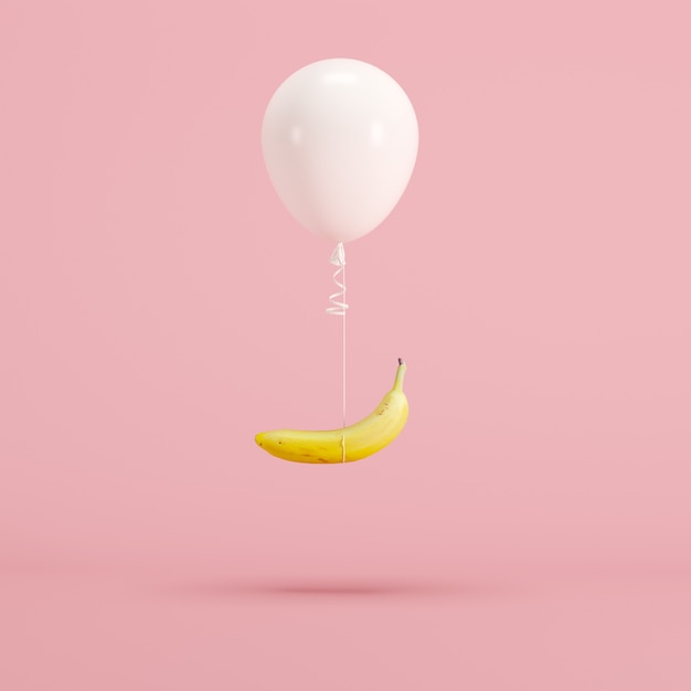 Balão branco e banana flutuando no fundo rosa