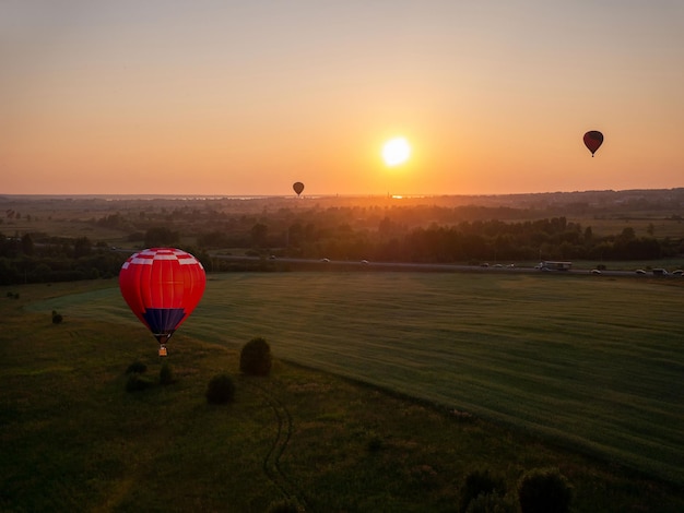 Balão de ar colorido está voando em voo livre sobre o campo Balão multicolorido no céu ao pôr do sol