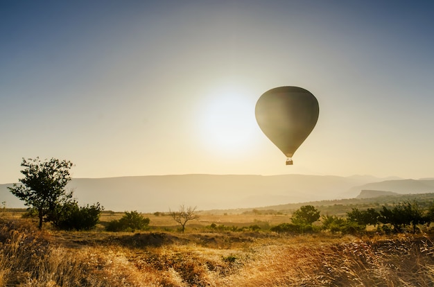 Balão de ar quente sobrevoando a paisagem rochosa na capadócia turquia