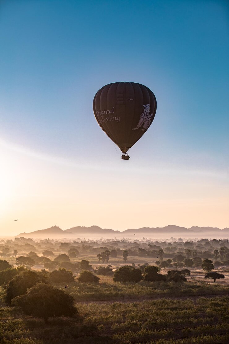 Foto balão de ar quente voando sobre a paisagem contra o céu claro
