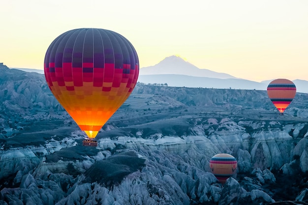 Balão de ar quente voando sobre a paisagem rochosa na Capadócia Turquia