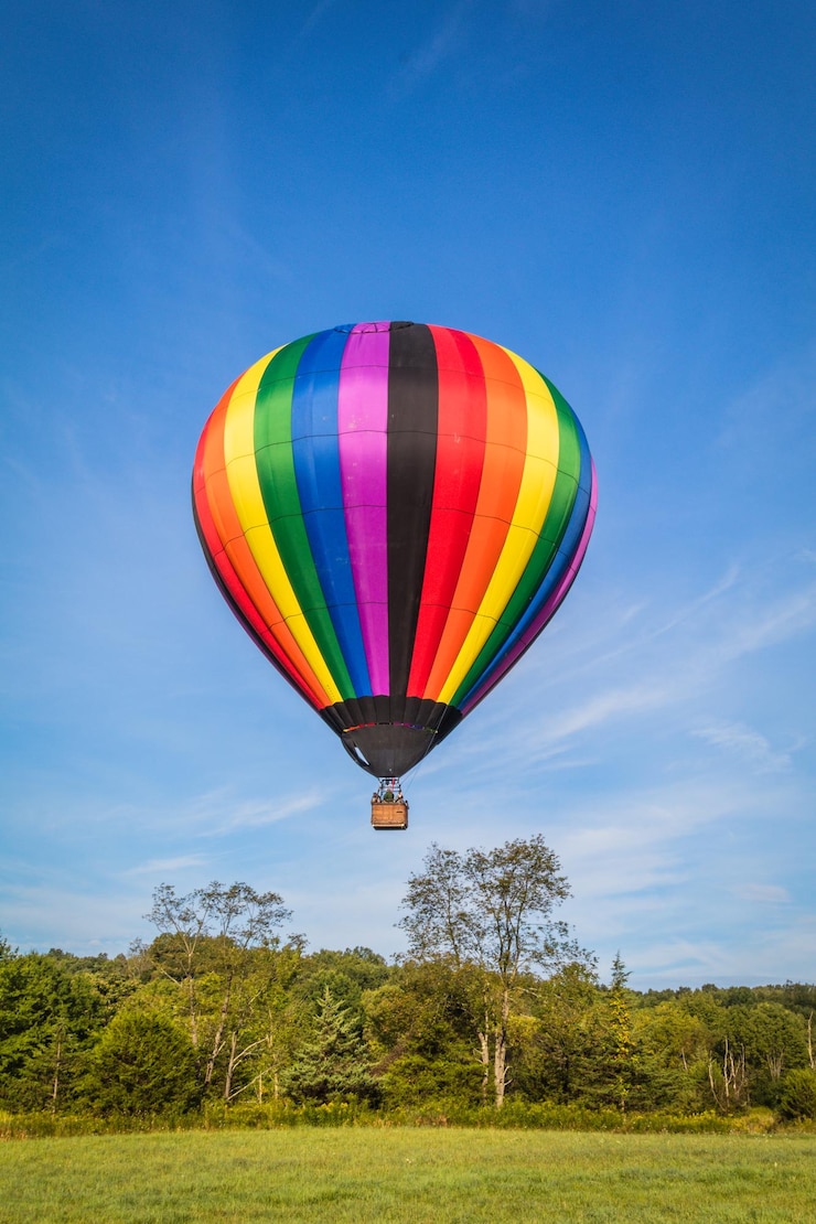 Foto balão de ar quente voando sobre árvores contra o céu