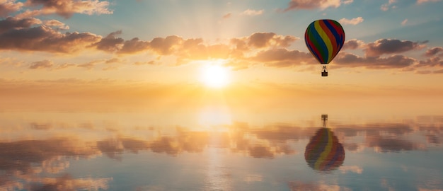 Balão de ar quente voando sobre o céu dramático do pôr do sol de águas calmas