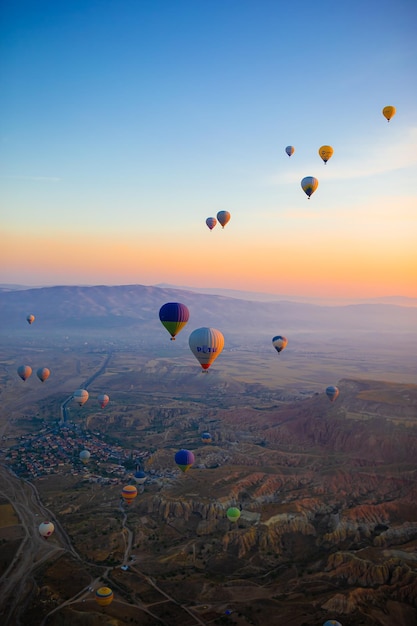 Foto balão de ar quente voando sobre paisagens rochosas na capadocia com um belo céu em fundo