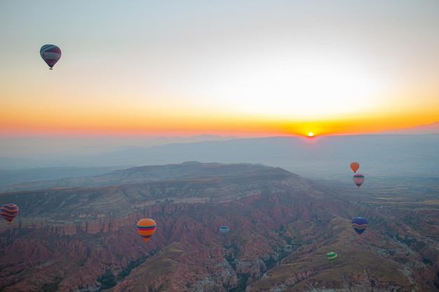 Balão de ar quente voando sobre paisagens rochosas na Capadócia Turquia