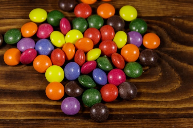 Balas coloridas em forma de botão com recheio de chocolate na mesa de madeira
