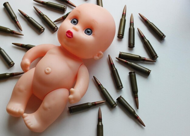Balas espalhadas em torno de boneca nua como símbolo de crianças vítimas da guerra