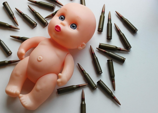 Las balas esparcidas alrededor de la muñeca desnuda como símbolo de los niños víctimas de la guerra