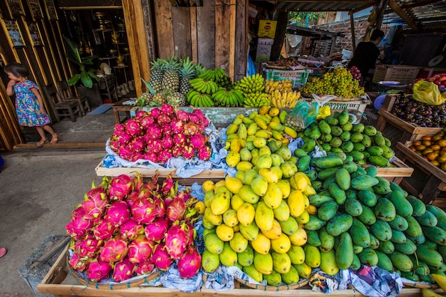 Balcão de mercado de frutas com pilhas de frutas suculentas manga, banana, fruta do dragão em Luang Prabang, Laos