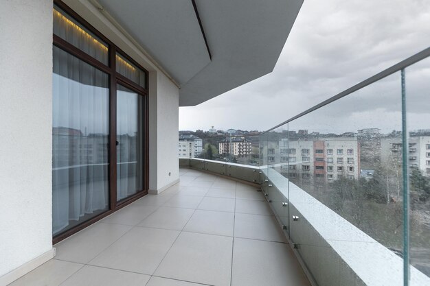 Balcón grande y espacioso en una casa nueva en clima lluvioso Interior de balcón vacío y barandillas de vidrio